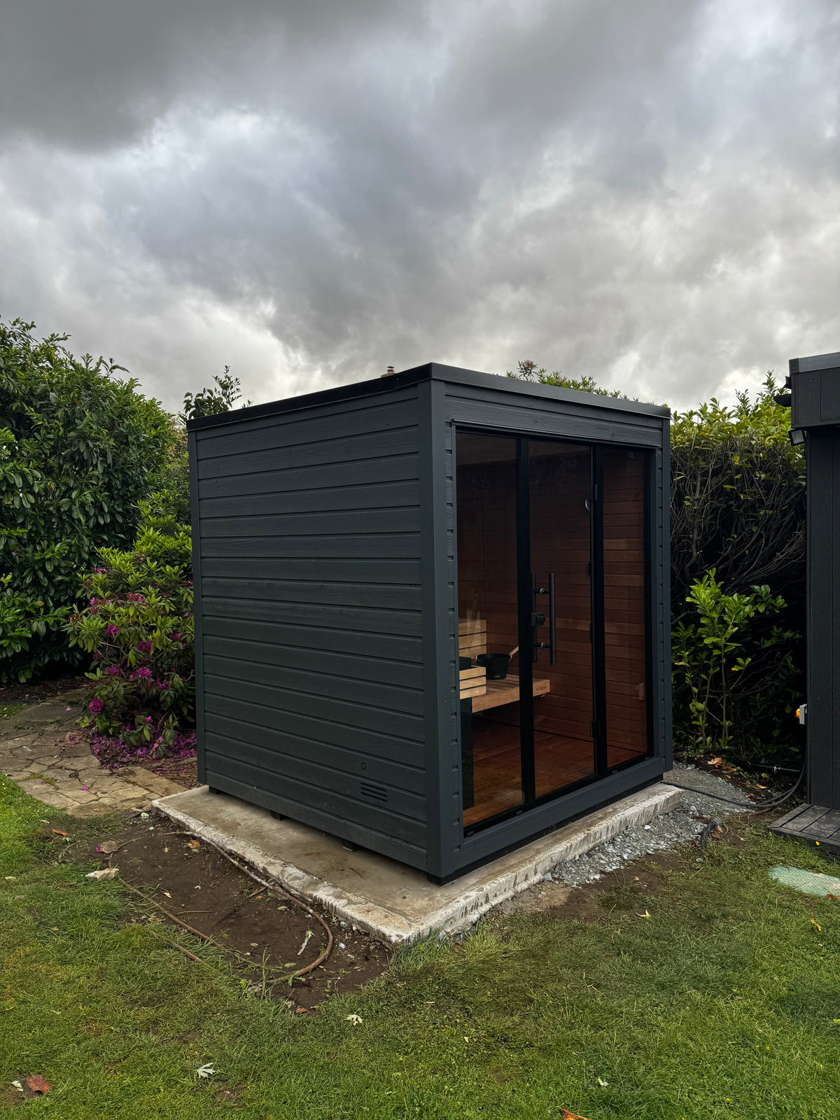 Completed dark-clad sauna within the residential garden